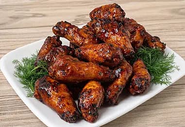 Spiced barbecue chicken wings arranged on a dark serving platter